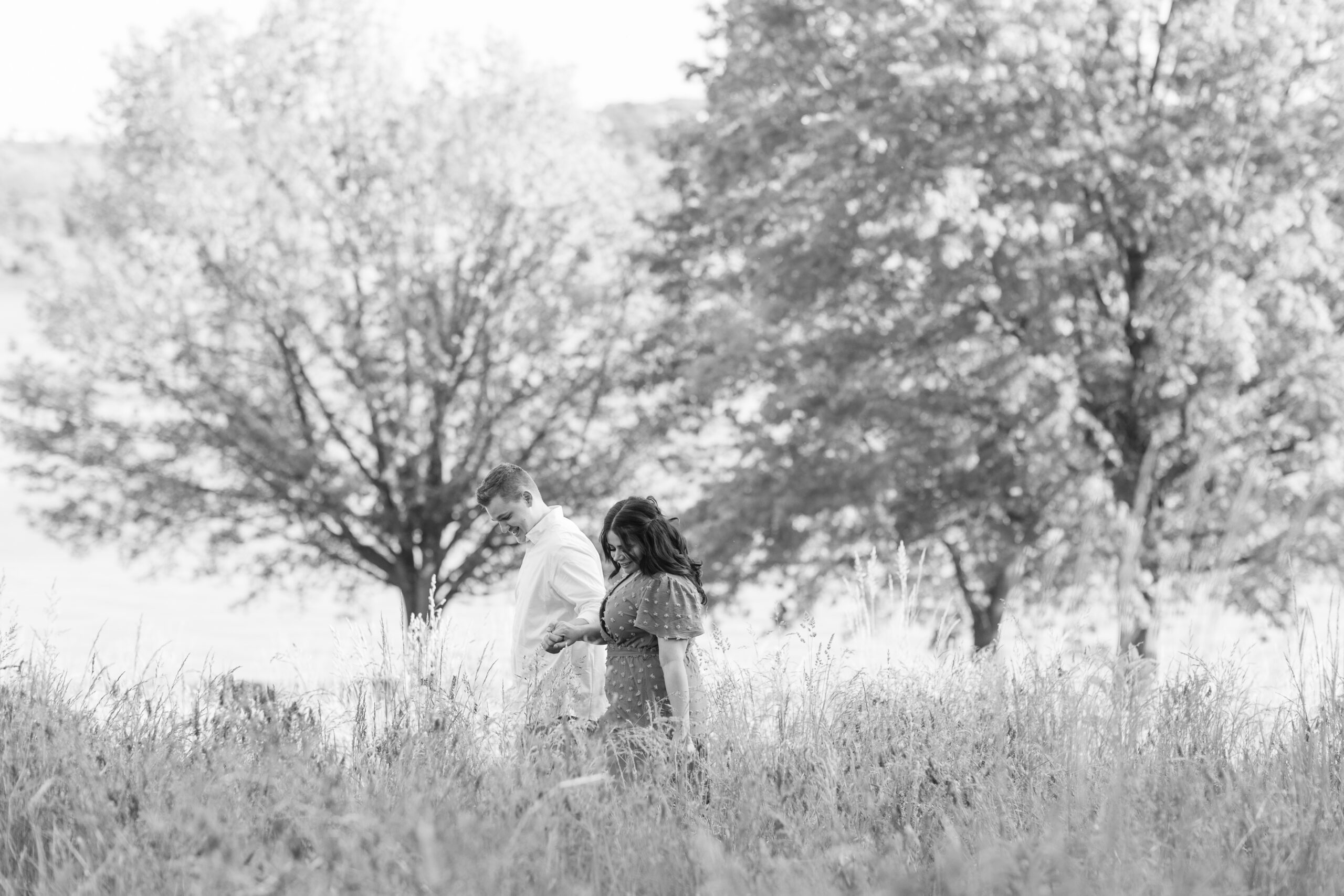 Engaged couple walking through wildflower field